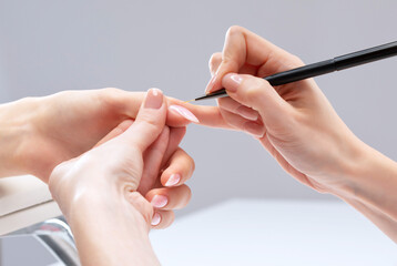The master of the manicure coats nails with gel polish in the beauty salon. Professional care for...