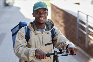 Portrait of smiling black man as food delivery worker in city