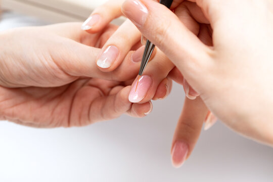 The master of the manicure coats nails with gel polish in the beauty salon. Professional care for hands.