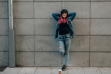 relaxed urban hipster girl on the street leaning on the wall