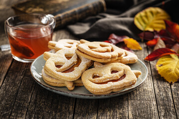 Linzer cookies in the shape of a Halloween pumpkin on wooden table.