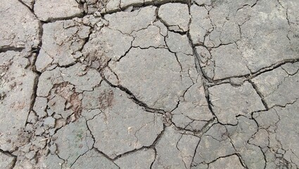 Dry earth ground parched black soil floor with crack or broken texture pattern. Closeup view of arid, barren or wasteland surface in hot summer climate. Drought, heatwave and global warming background