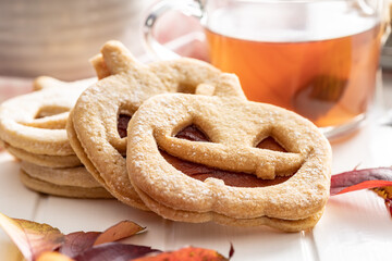 Linzer cookies in the shape of a Halloween pumpkin on white table.