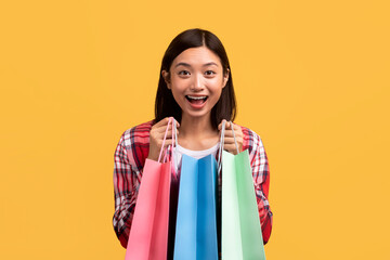 Satisfied customer. Overjoyed chinese lady opening colorful shopping bags, happy with her purchases