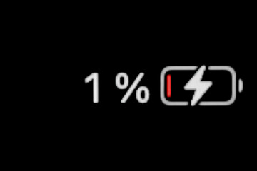 Low level of smartphone charged battery level indicator - charging process - one, 1 percent: close...
