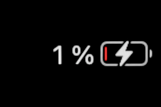 Low level of smartphone charged battery level indicator - charging process - one, 1 percent: close up macro view of gadget display, screen. Energy, technology, power, digital and symbol concept