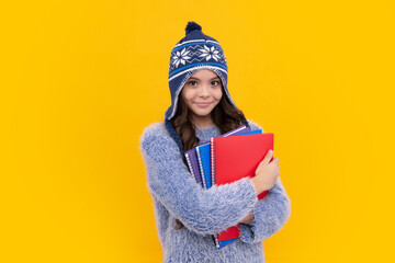 Schoolgirl child student with backpack and warn hat, isolated yellow background. Learning and knowledge education concept. Happy face, positive and smiling emotions of teenager girl.