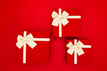 Red gift boxes tied with golden ribbons on a red background