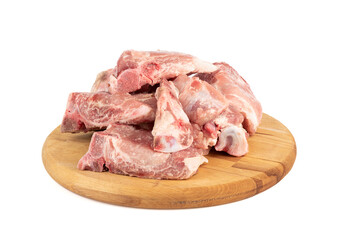 Pieces of pork stew on a round cutting board over a white background.
