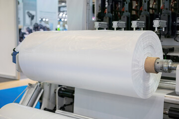 Automatic plastic bag making machine: moving roller with flat polyethylene transparent film at...