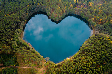 Wonderful heart shape lake surrounded by trees and nature in the middle of the forest. Concept of earth day, environment and ecology, love.