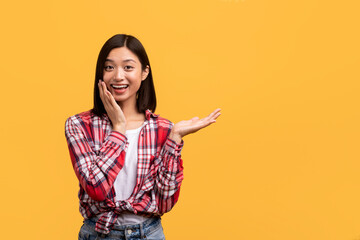 Wow, look here. Young chinese lady holding hand with open palm, showing free space and touching her...