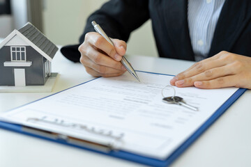 A businesswoman signing a new home purchase or sale from a real estate agent provides tax advice and details of the deal discussed.