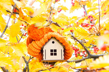 Toy house and chunky warm hat in autumn foliage