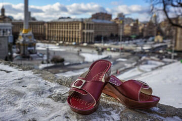 a pair of slippers on the snow with the skyline of Kyiv in the back, before the war