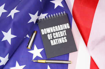 On the American flag lies a pen and a notebook with the inscription - downgrading of credit ratings