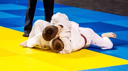 Two boys fighter judoka in judogi compete on the tatami 