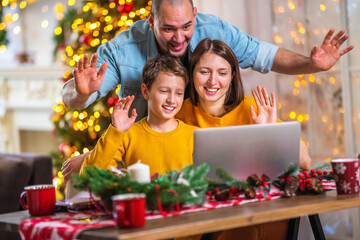 Portrait of a loving full happy family sitting on the couch talking with a laptop calling video conferencing , making online purchases during the New Year holidays. Christmas sales