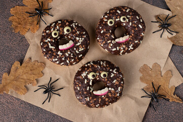 Halloween festive donuts with eyes and teeth on brown background