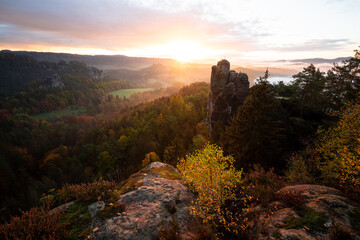 Sonnenaufgang mit Wolken und Nebel im Herbst auf der Bastei mit Blick auf den Mönch im...