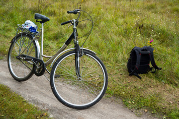 Fototapeta na wymiar While the tourist is resting… Bicycle and backpack by the meadow road. 