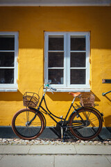 Fahrrad vor gelber Hauswand mit weißen Sprossenfenstern