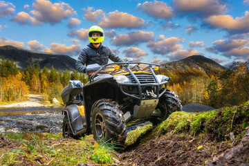 ATV rider man participates in motocross. ATV rides near forest. Man in yellow helmet for quad...