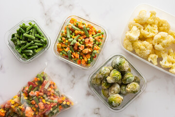 Frozen vegetables in containers and bags, frozen cauliflower and asparagus beans, peas and corn, Brussels sprouts and carrots, mix of vegetables, top view, copy space
