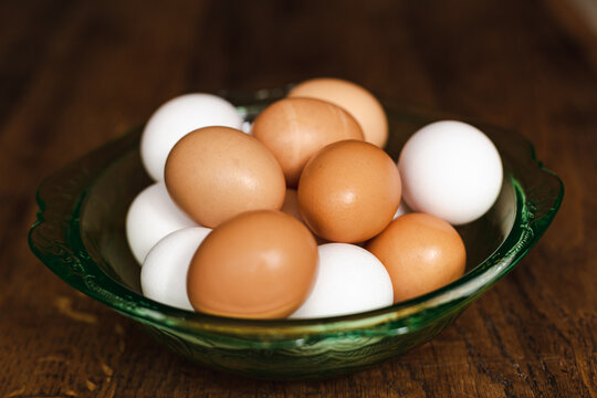 Bowl of fresh brown and white chicken eggs on wooden table