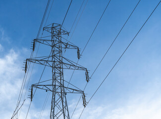 Electric station for supplying electricity to city, village. High voltage electric tower. Close-up. Power line against blue sky. 