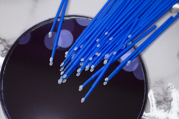Set of blue microbrushes for eyelashes on a mirror background with bokeh