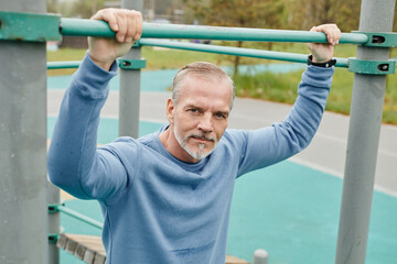 Portrait of active mature man working out outdoors and looking at camera in minimal city setting