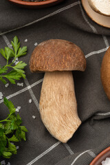 Culinary background with porcini mushrooms, wooden board and spices on a light gray background