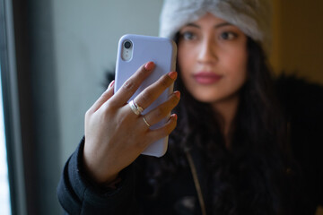 Fototapeta premium Beautiful latina girl is shopping in a mall, taking a selfie and wearing a hair band.