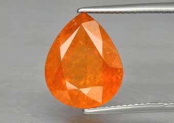 Natural stone orange spessartine garnet on a gray background