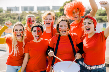 Group of young sports fans in red jerseys have fun and cheer on their team