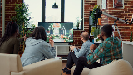 Group of friends playing video games competition and winning, having fun at hangout and drinking beer. People enjoying online challenge win on television console, leisure activity.
