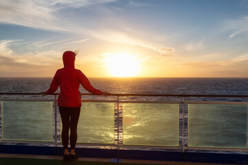 Adventure woman traveler enjoying colorful sunset from a Cruise Ship. North Atlantic Ocean. Travel Concept