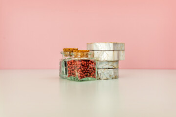 Glass jars with spices and mother-of-pearl boxes on a neutral surface