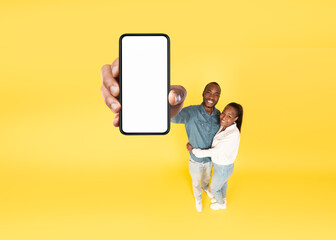 Fototapeta na wymiar African American Couple Showing Huge Smartphone Screen Over Yellow Background