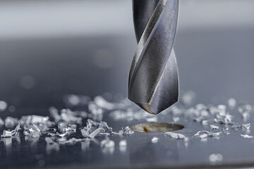 metal drill bit make holes in steel billet on industrial drilling machine with shavings. Metal work...