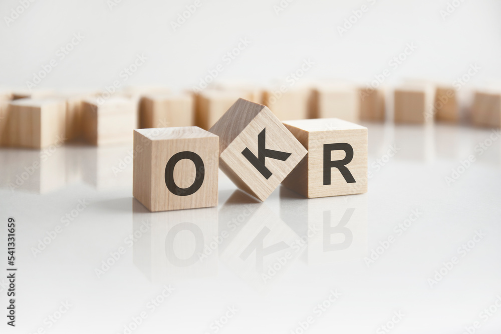 Aufkleber text okr on wooden blocks with letters on a white background. reflection of the caption on the mirro