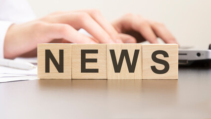 man made word NEWS with wood blocks on the background of the office table. selective focus. business concept.