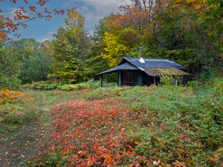 Primitive cabin at Lake Katahdin, Maine, in early fall surrounded by brilliant fall foliage