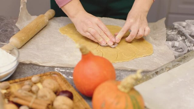 woman cutting cookies from handmade dough with pastry cutter pumpkin biscuits baking home kitchen autumn seasonal decoration making ghost monster cookies for halloween party celebration trick or treat