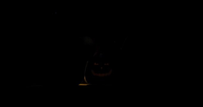 Halloween pumpkin with scary eyes in the dark vintage  room, spotlight over the top | wide steady shot 4k 12-bit footage