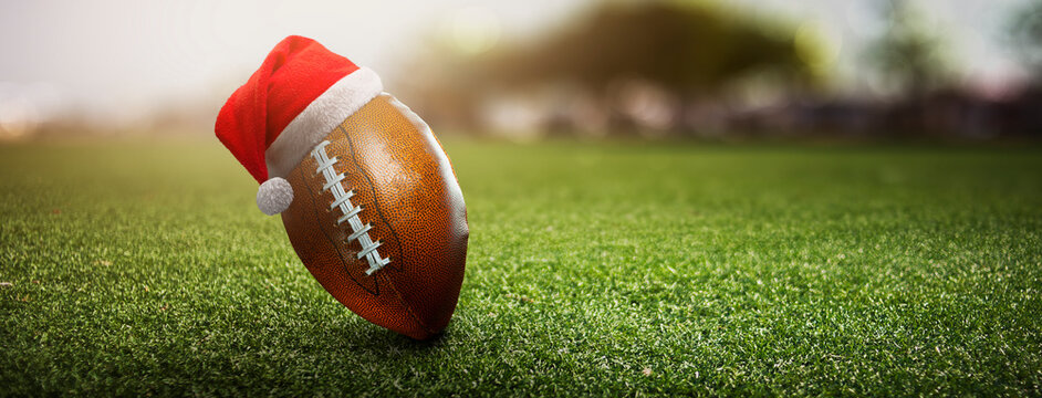American football ball on the grass of a stadium with christmas hat