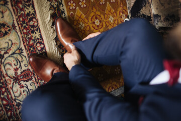 Brown leather shoe lacing. Businessman in white shirt and suit trousers. Groom getting ready for...