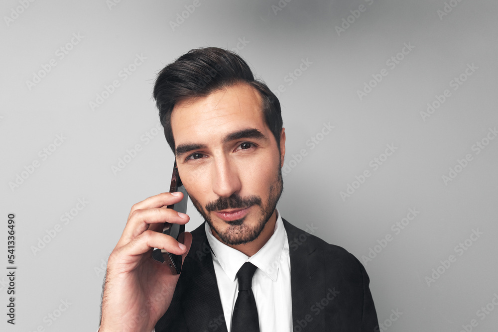 Poster man businessman in a suit talking on the phone solving important issues in wide angle on a gray back