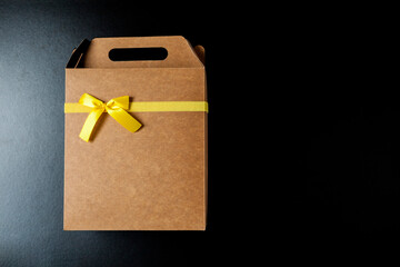 Gift wrapping with a yellow bow and black background. Seen from above. Copy space. Gift concept. Yellow bow concept.